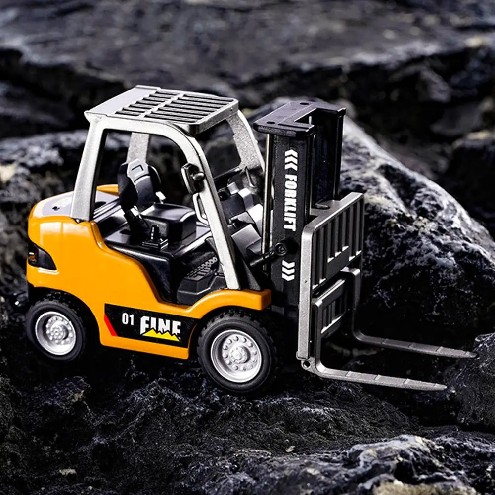 Un petit camion à mât rétractable jaune, modèle télécommandé, sur une surface rocheuse sombre.