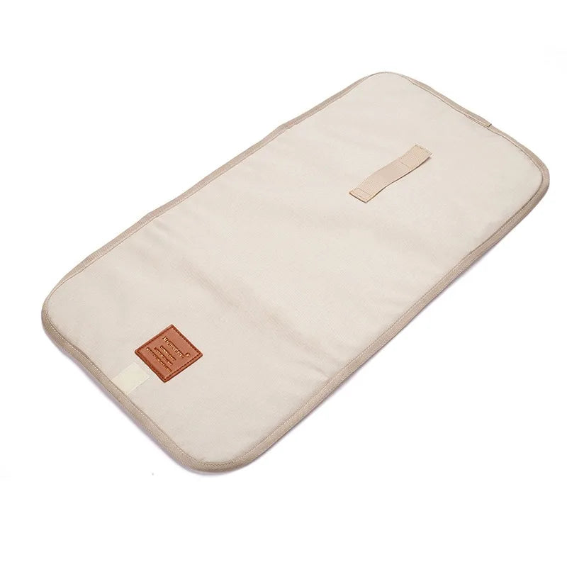 Beige faltbare wasserdichte Wickelunterlage mit kleinem Riemenbesatz.