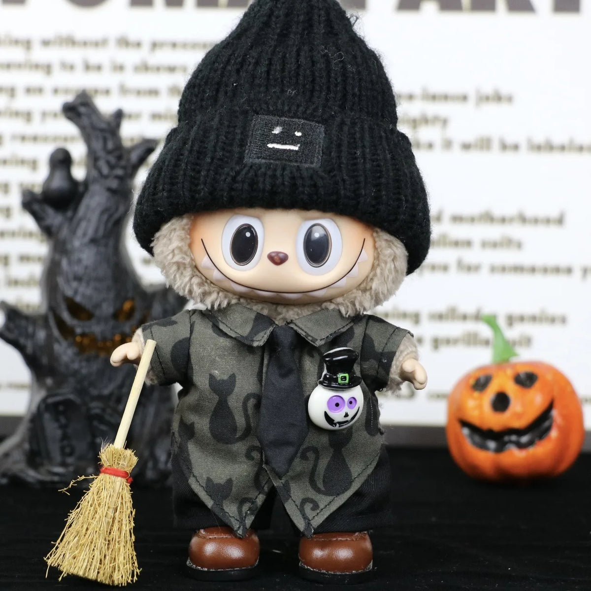 A small doll dressed as a Halloween pumpkin with a black knitted hat and green costume details.