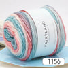 A spool of gradient rainbow yarn with pink, blue, and red strands resting on a light blue surface.