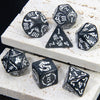 A set of black marble dragon pattern polyhedral dice resting on a white textured surface.