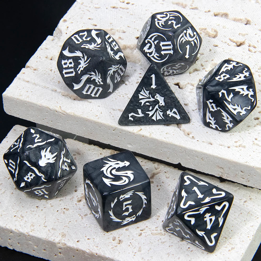 A set of black marble dragon pattern polyhedral dice resting on a white textured surface.