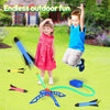 A boy and a girl are playing with an air-powered stomp rocket launcher and various related accessories in a green yard.