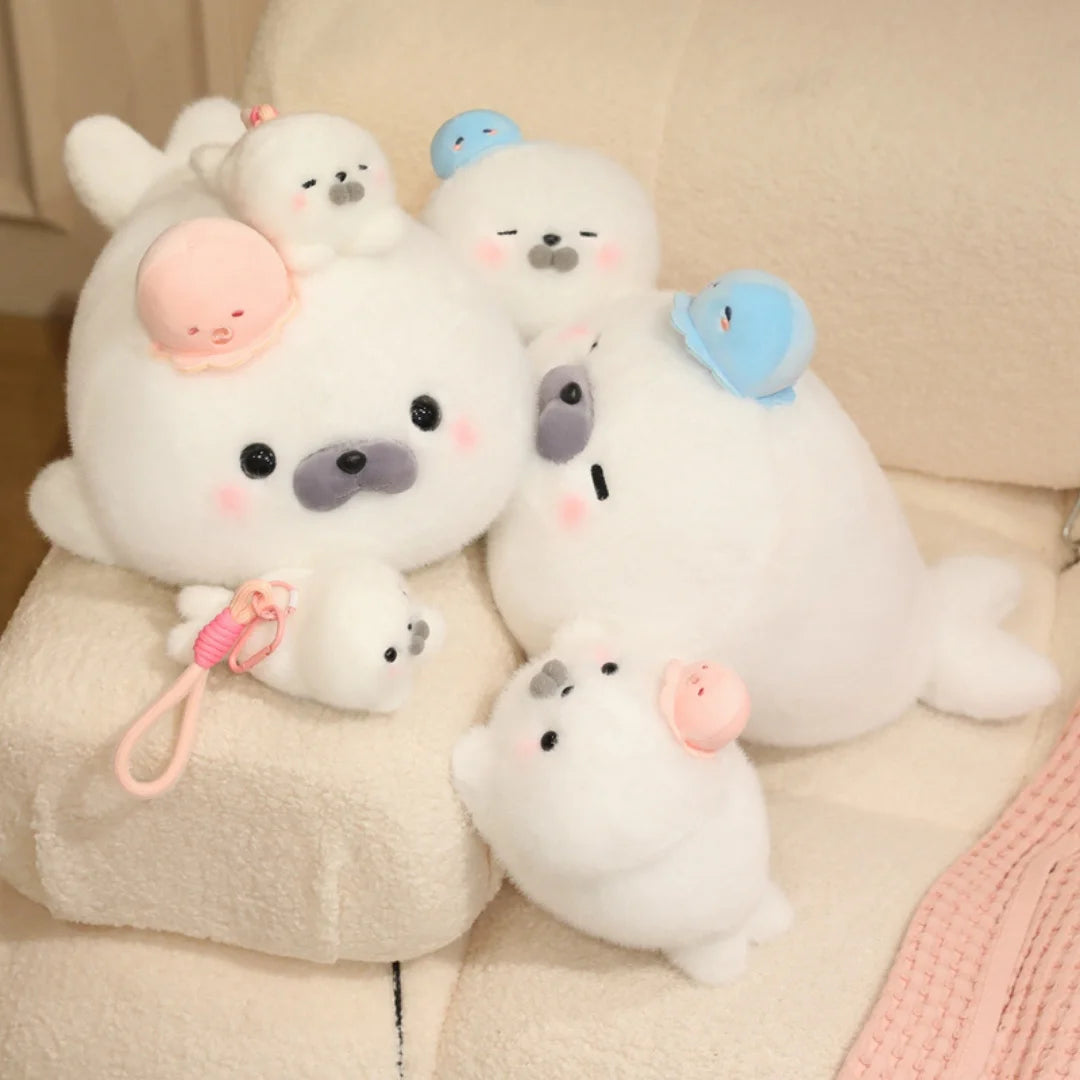 A collection of white seal plush toys with various colored hats, including pink and blue.