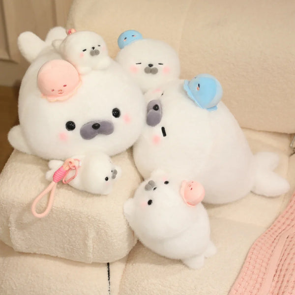 A collection of white seal plush toys with various colored hats, including pink and blue.