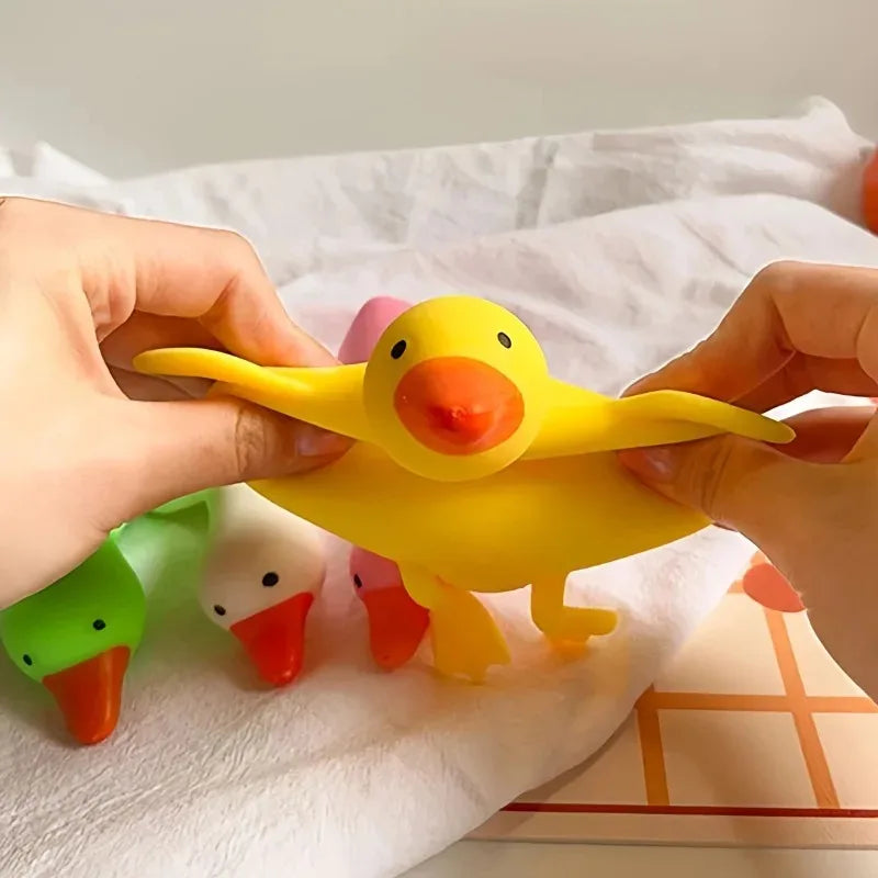 A hand is holding a yellow squishy duck toy against a white towel.