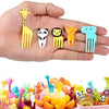 A hand holds a set of colorful mini fruit forks shaped like various animals, including a giraffe, panda, lion, and elephant.