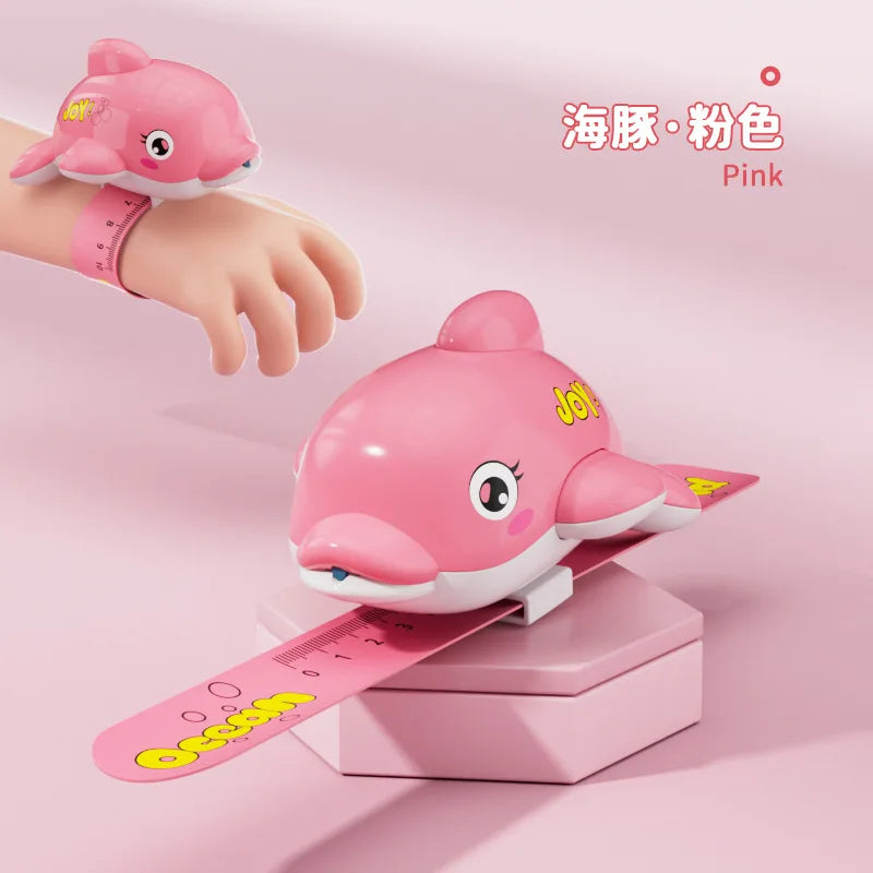 Pink turtle-shaped water gun toy resting on a ruler and hand for scale.
