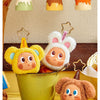 A yellow plush bear and a brown plush bear are displayed next to a green pot, with small colored lids in the background.