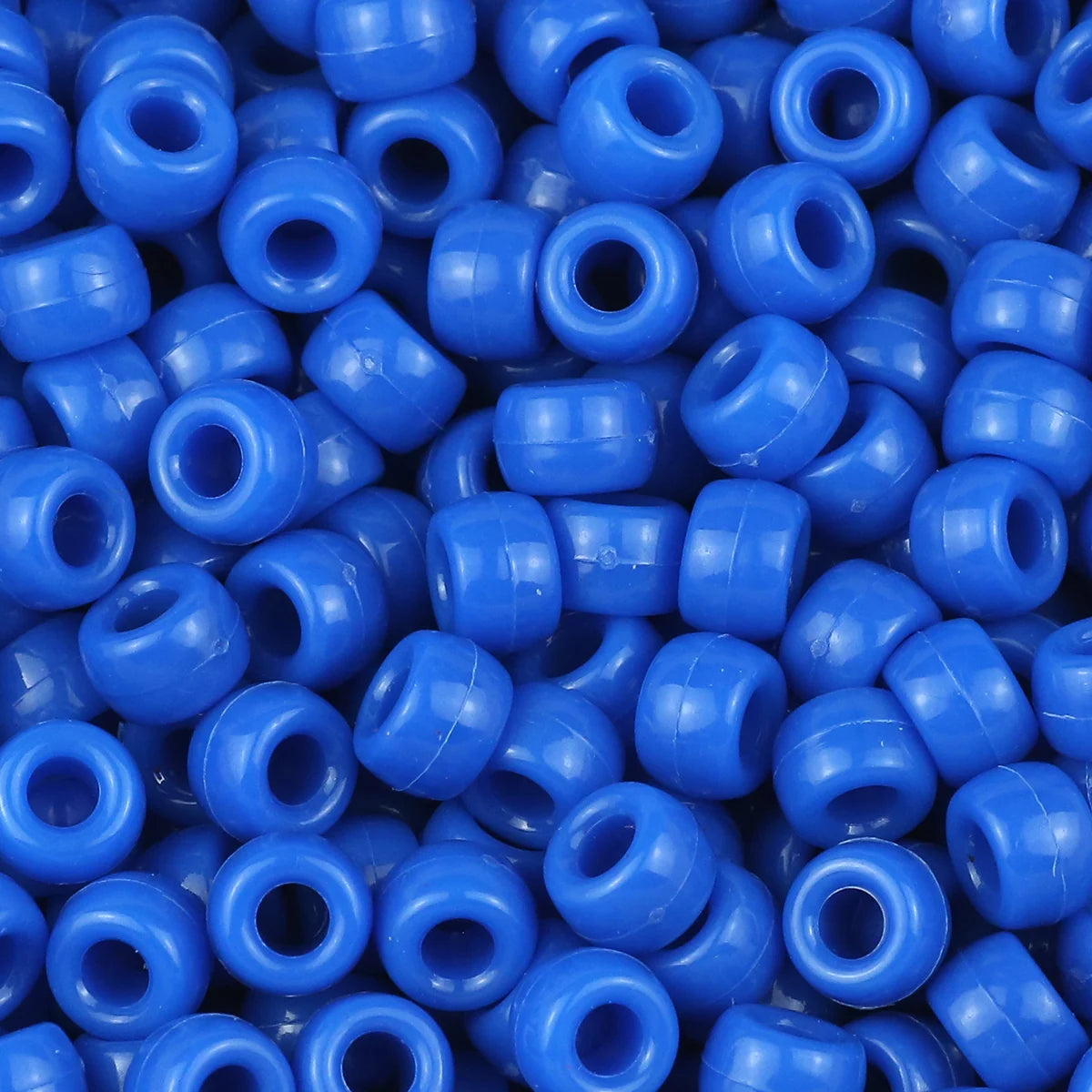 A close-up view of small, solid blue pony beads for jewelry making and craft projects.