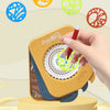 A hand is using a yellow Spirograph drawing set to create colorful geometric patterns on a page.