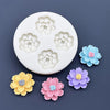 A white silicone mold with five embossed daisy flower shapes in varying shades of light green and blue, alongside colorful fo