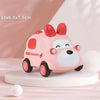 A pink ambulance toy car with red ears and lights is displayed on a white surface.
