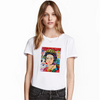 A woman models a white t-shirt featuring a colorful, vintage-style graphic print on the front.