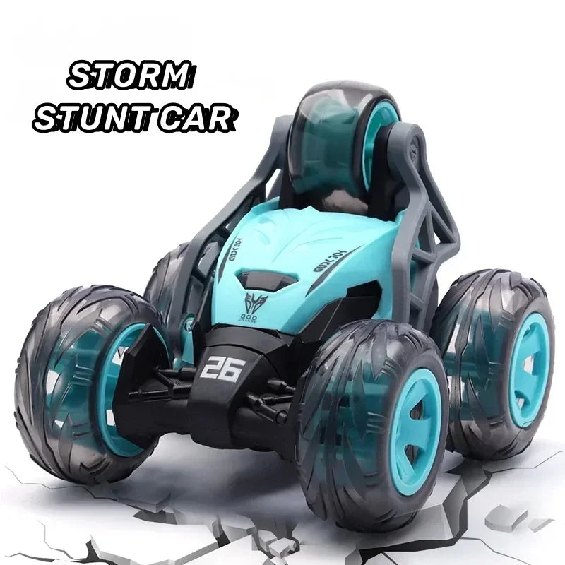 A black and teal remote control stunt car with large tires is shown on a cracked surface.
