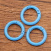 A set of ten light blue metal O-ring spring clasps arranged in a cluster on a wooden surface.