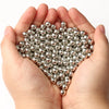 A pair of hands holds a pile of round silver spacer beads for DIY jewelry making