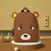 A brown bear-themed kids backpack with large ears sitting on a wooden surface.