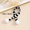A black and white striped knit headband with white pom-poms, shown on a light background.