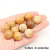A collection of smooth, spherical Yellow Aventurine crystals held in a person's hand.