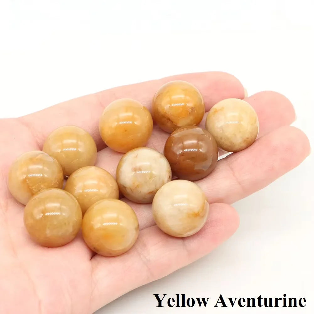 A collection of smooth, spherical Yellow Aventurine crystals held in a person's hand.