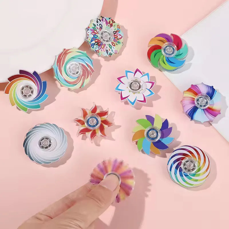 A collection of colorful mini rainbow fidget spinners arranged on a pink background.