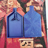 A pair of blue plastic trays with pop-up plugs for bead sorting placed on a diamond painting fabric.