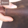 A hand is holding a piece of brown leather, showing the texture and color for crafting.