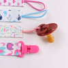 A set of four soft pacifier clips with double-sided prints in pink, blue, and white patterns.