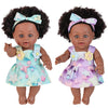 A realistic 12-inch African American baby doll with curly hair wearing a purple and light blue dress and bow
