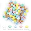 A collection of colorful silicone lentil beads in various shades including pink, blue, yellow, and white arranged on a wooden