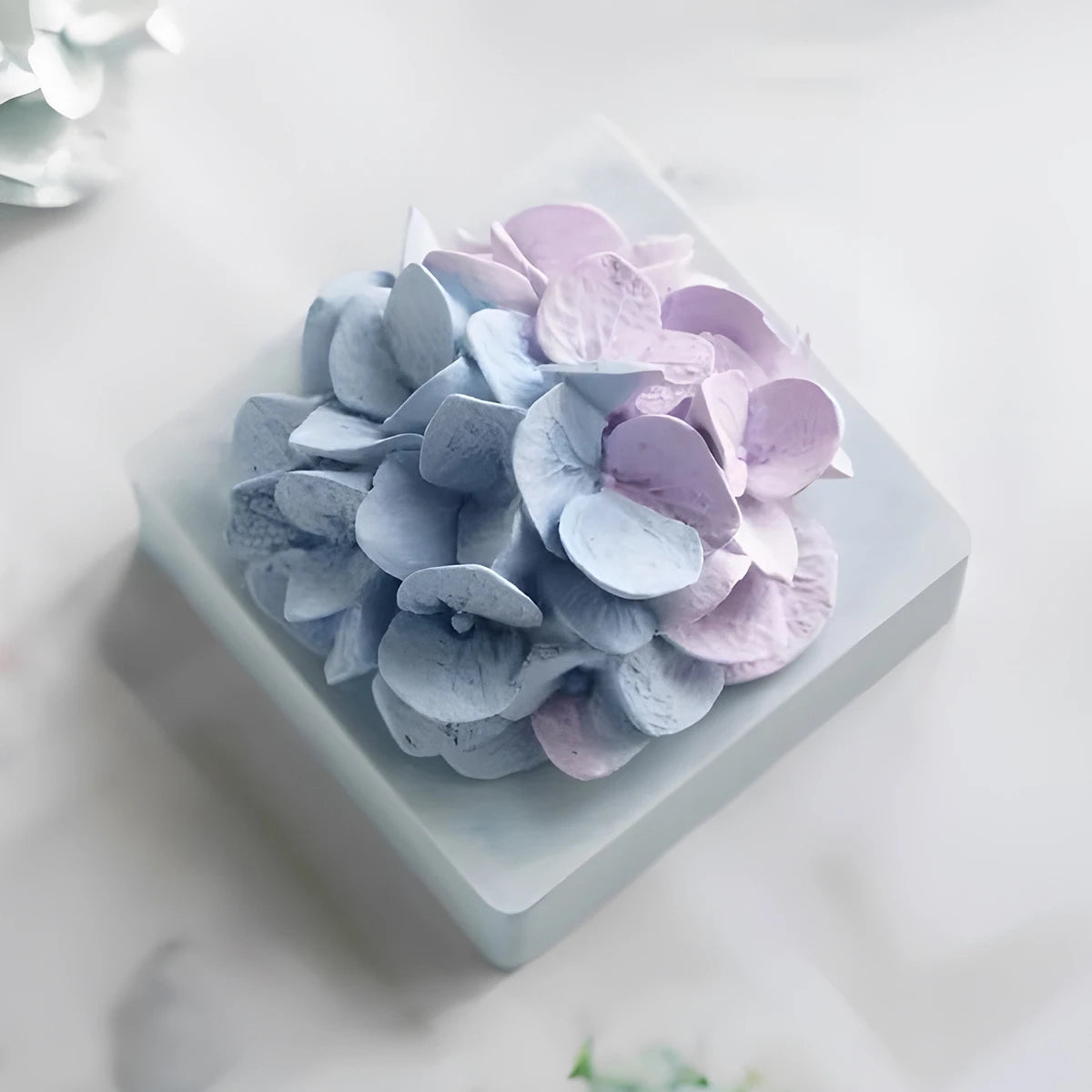 A cluster of light purple and blue flower petals arranged on a square white dish.