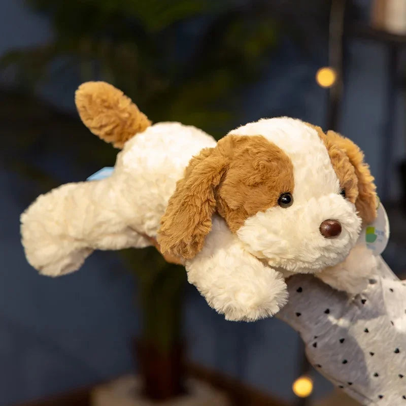 A fluffy, light-colored dog plush toy with brown floppy ears is lying down against a dark background.