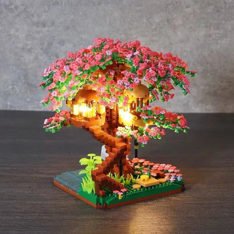 A miniature sakura tree built from wooden blocks with pink flowers and glowing lights.