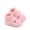 A pair of pink knitted baby booties shaped like a lamb or bunny with a ribbed cuff.