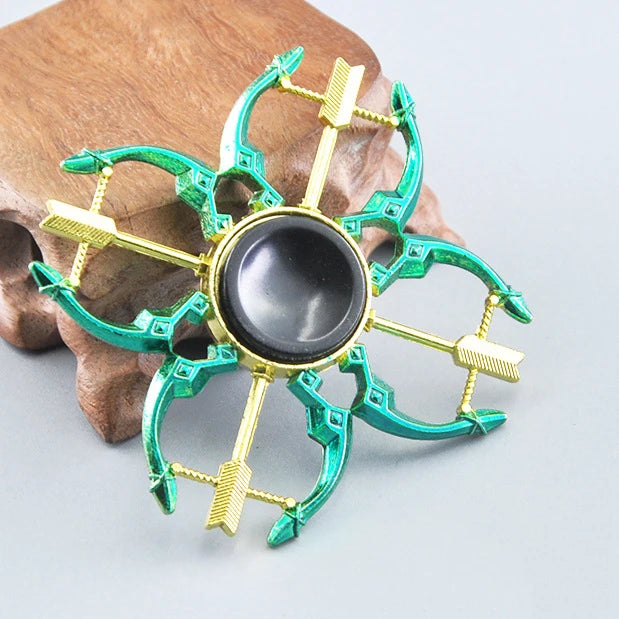 A metal fidget spinner with a rainbow green finish and a black center, resting on a wooden surface.