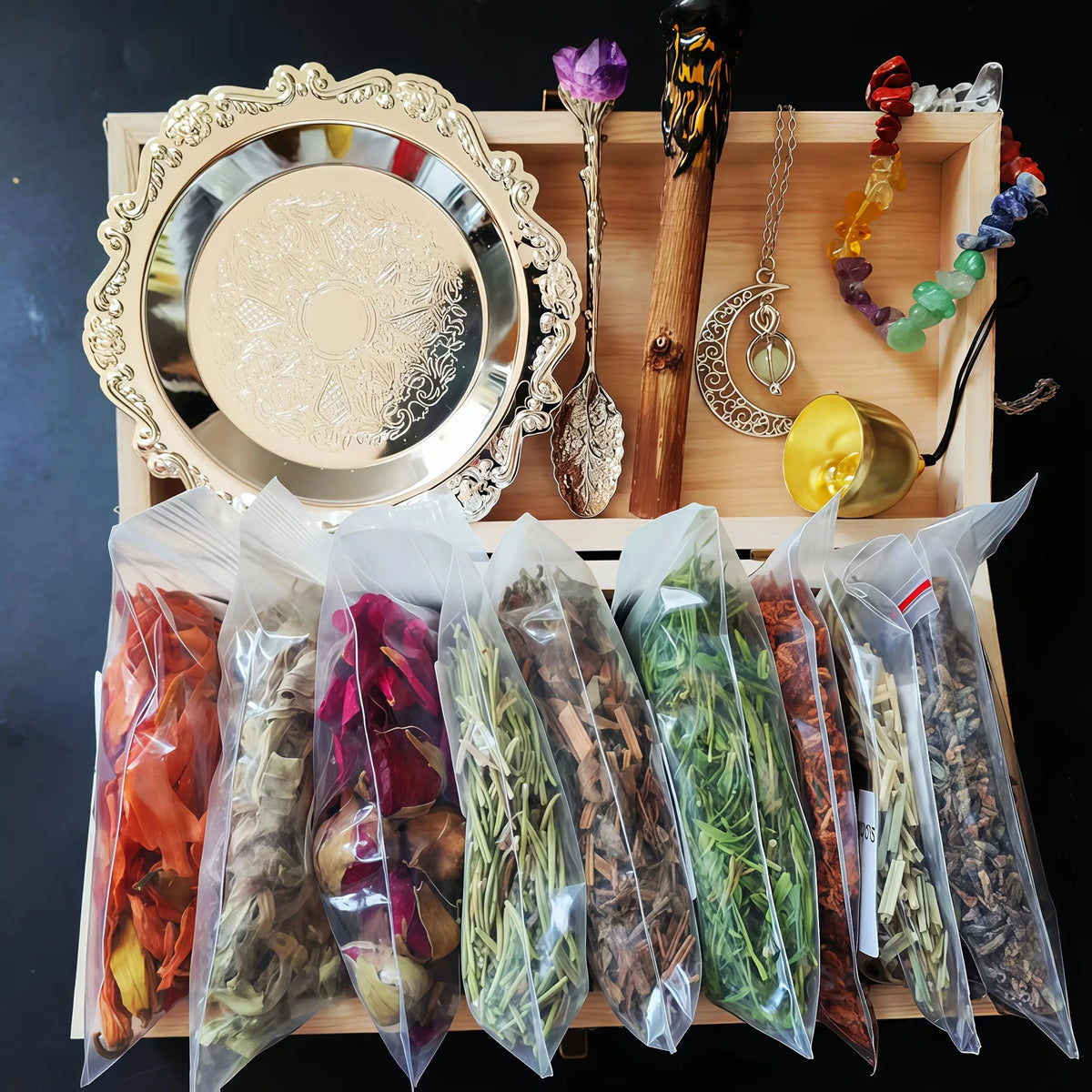 A witchcraft starter kit displayed in a wooden box featuring crystals, herbs, and a decorative mirror.