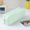 A light green and white striped canvas pencil case with a zipper is shown on a white surface.