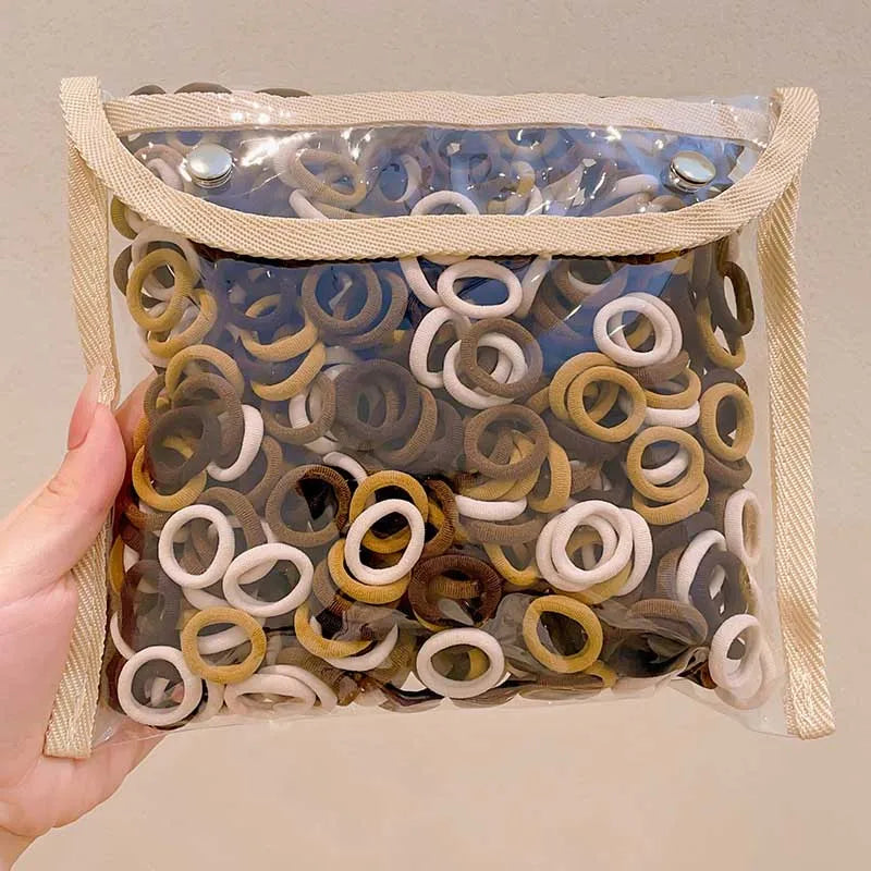 A clear plastic bag filled with a multi-pack of colorful nylon hair ties in various shades of brown, beige, and white.