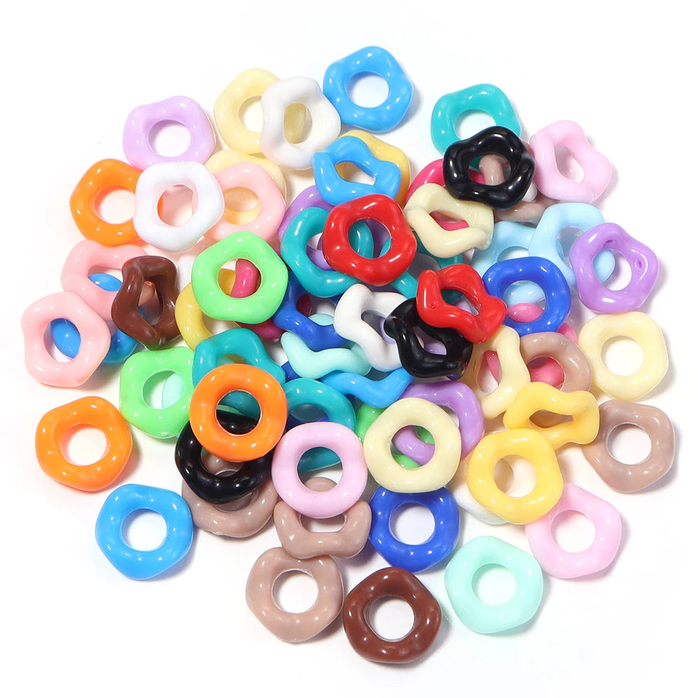 A pile of colorful acrylic doughnut spacer beads in various shades including pink, yellow, green, blue, and black.