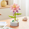 A pink rose flower building block bouquet set with green stems and leaves on a wooden table.