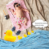 A baby wearing sunglasses is sitting on a red and white striped mat surrounded by rubber ducks and fabric.