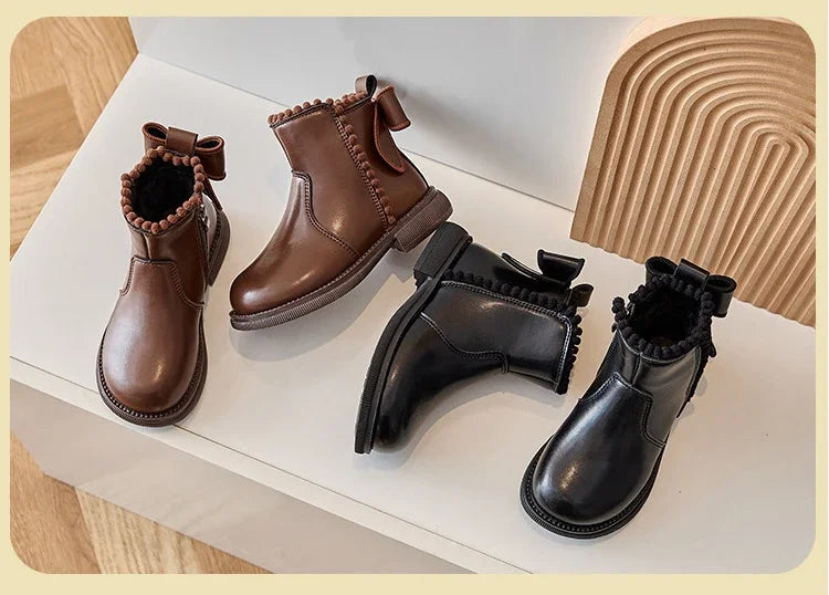 A collection of brown and black girls' ankle boots featuring bow-knot details and side zippers displayed on a white surface.