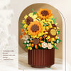 A bouquet of DIY rose and sunflower building blocks in orange, yellow, and brown arranged in a dark pot.