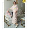 A woman models a light pink and white striped short-sleeve lounge dress indoors.