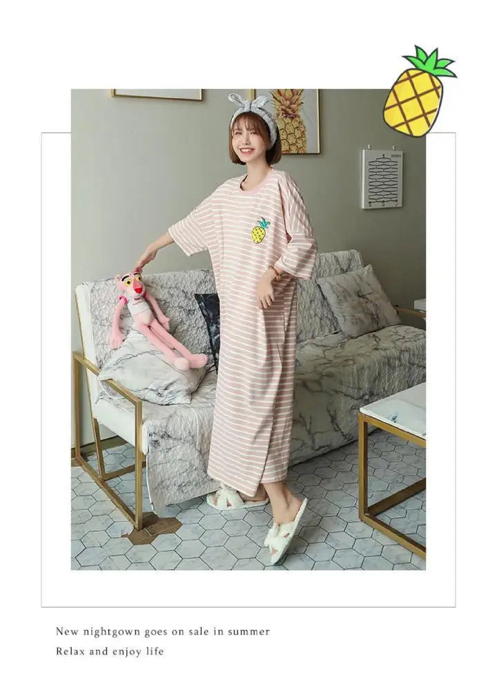 A woman models a light pink and white striped short-sleeve lounge dress indoors.