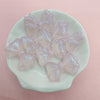 A collection of shimmering pink and iridescent mermaid bowknot beads arranged on a white oval dish.