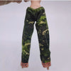 A doll wearing a green and camouflage patterned long-sleeved outfit.