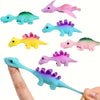 A collection of six colorful mini dinosaur finger slingshots in various shades of green, pink, yellow, and blue.