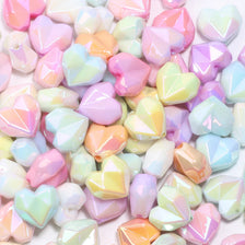 A pile of shiny, iridescent heart-shaped acrylic beads in various pastel colors for jewelry making